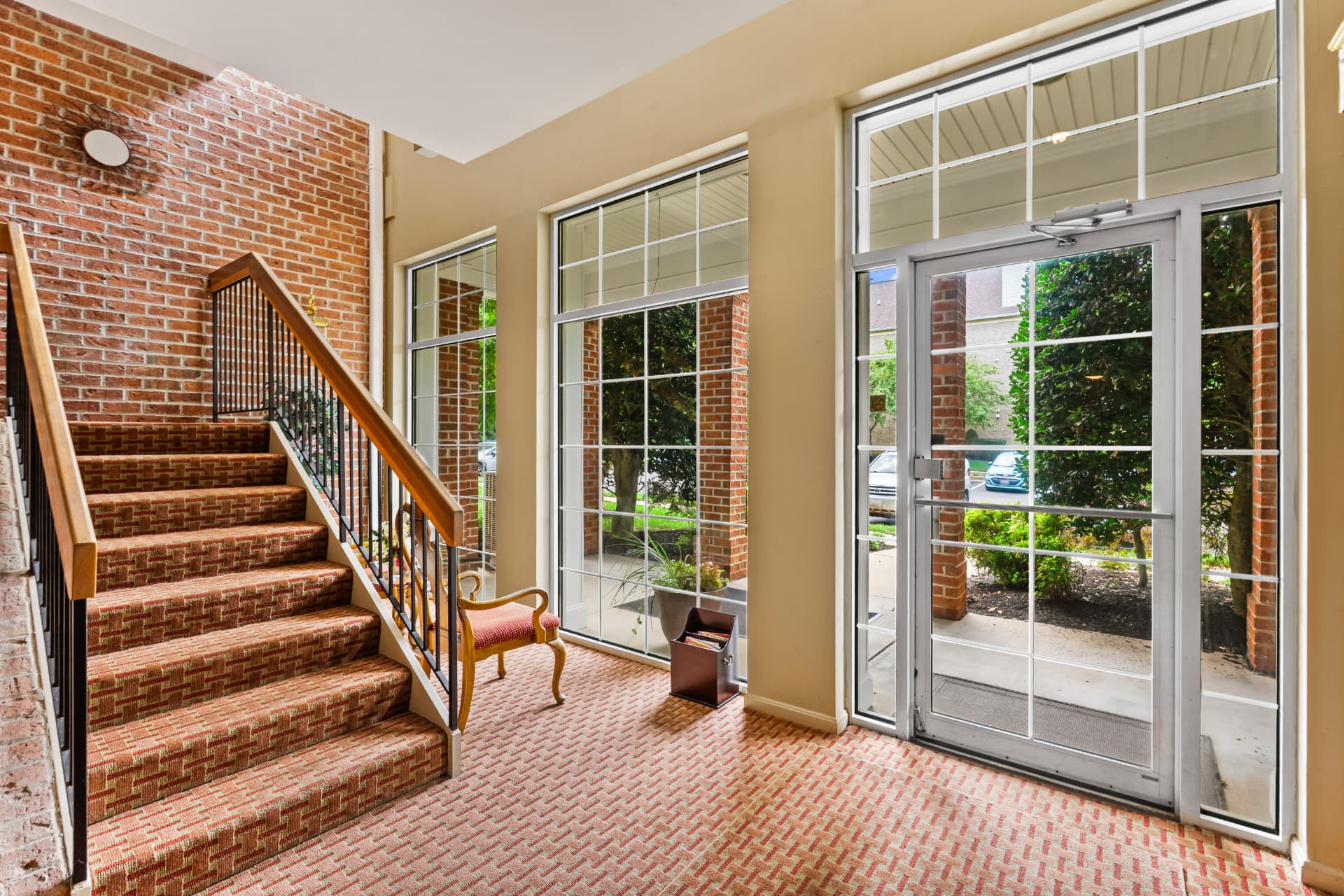 508 Limerick Circle Unit 303 — building lobby with exposed brick wall, staircase and floor-to-ceiling windows
