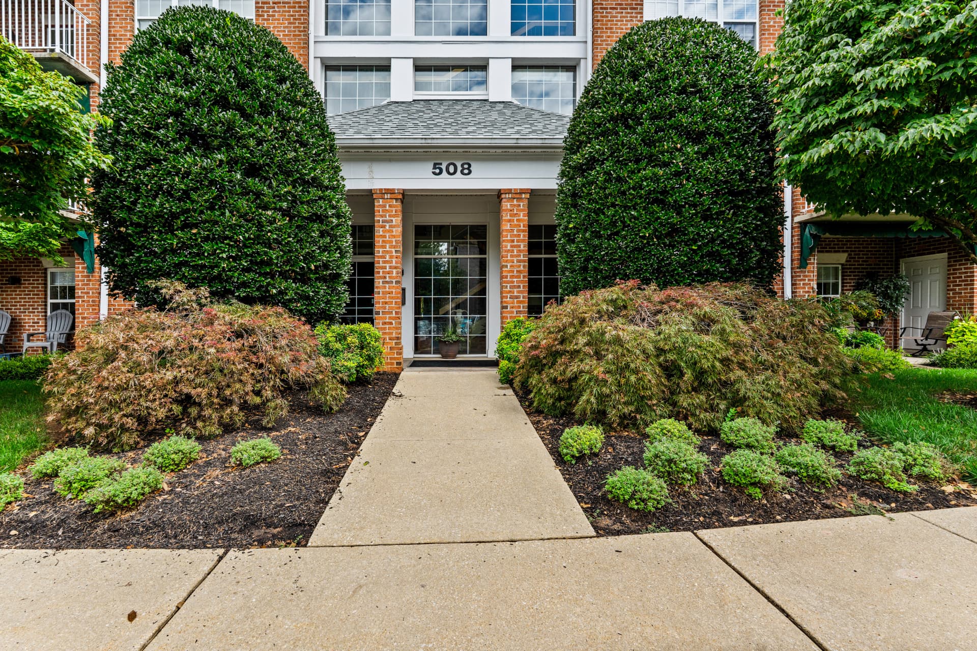508 Limerick Circle Unit 303 — landscaped walkway leading to the building's front entrance
