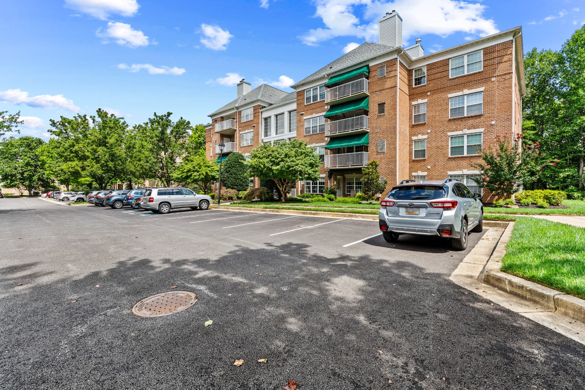 508 Limerick Circle Unit 303 — brick condominium building exterior with green awnings and parking