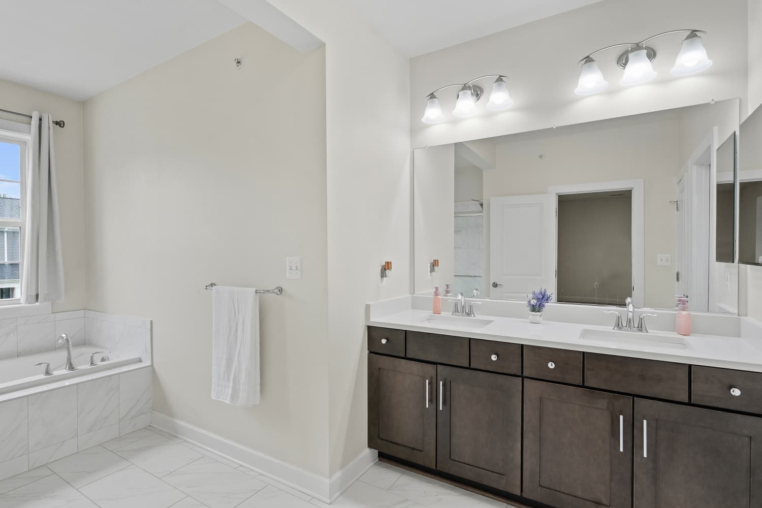 Primary bathroom with double vanity, large mirror and soaking tub