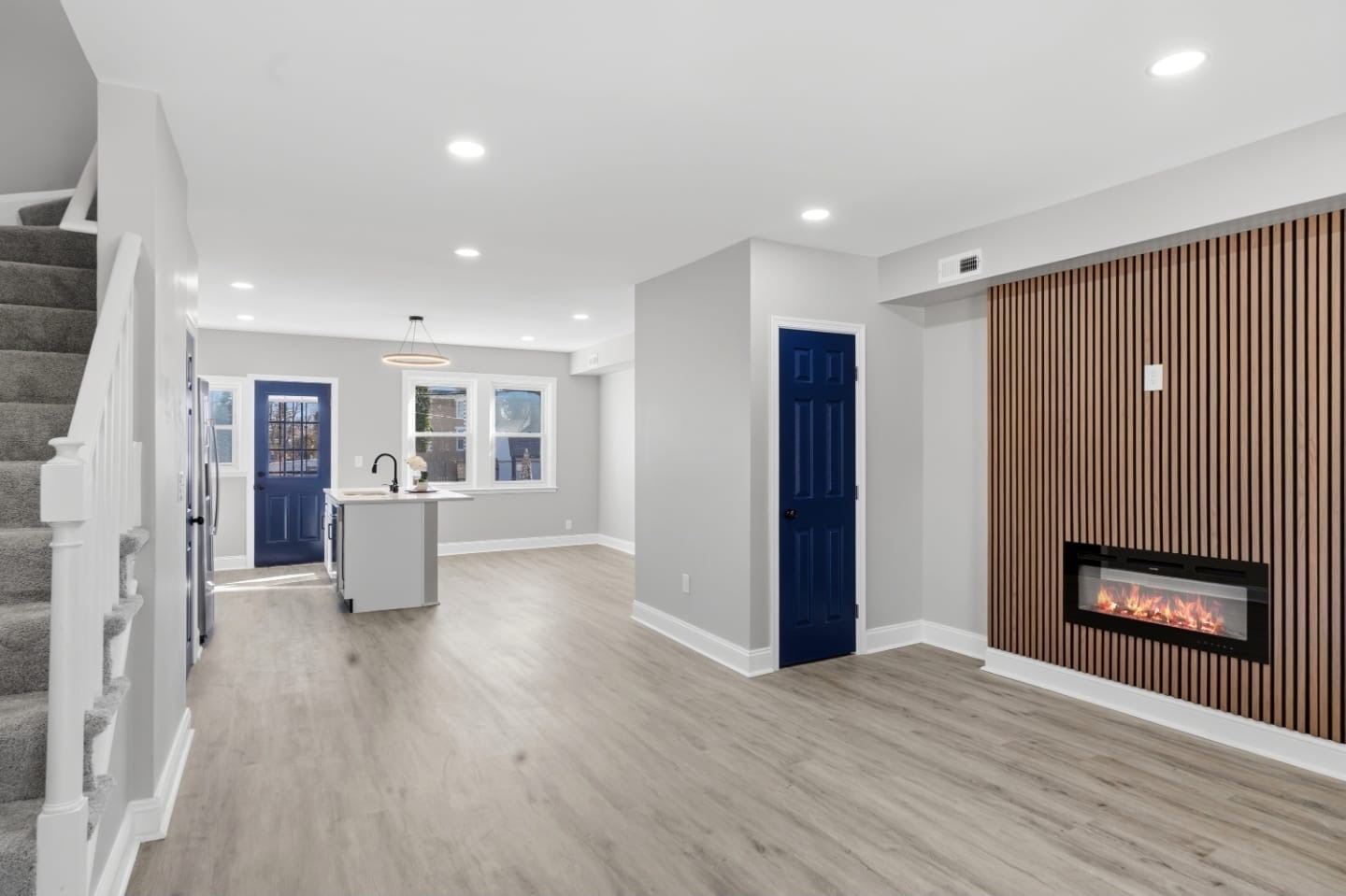 Open living area with slat wood fireplace wall leading to the kitchen